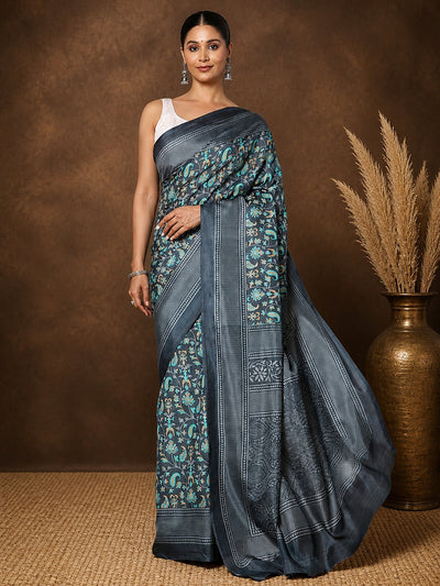 Charcoal grey printed saree with teal and gold botanical motifs and a large paisley medallion pallu.